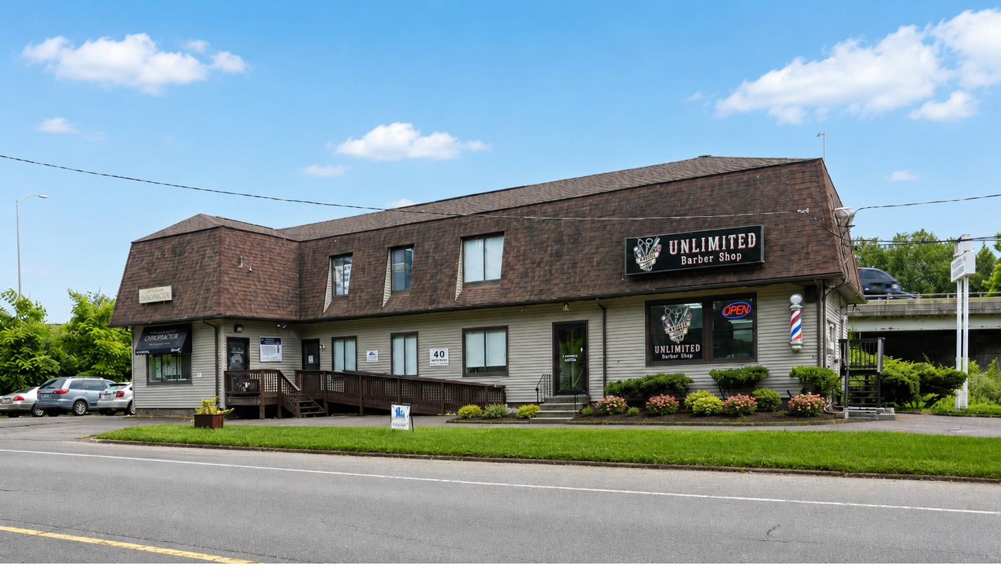 Exterior of Unlimited Barbershop at 40 Lake Ave Ext in Danbury, CT, with its sign and barber pole